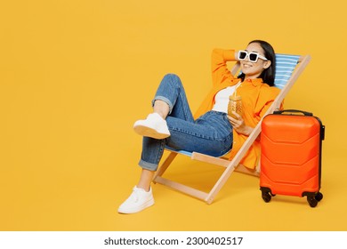 Young fun woman wear summer clothes sit in deckchair hold hand behind neck isolated on plain yellow background. Tourist travel abroad in free spare time rest getaway. Air flight trip journey concept - Powered by Shutterstock