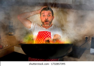 Young Funny And Desperate Man In Cooking Apron Holding Pan In Flames In Stress And Fear Making A Mess Of Fire And Smoke With Food Burning - Disaster Home Cook At Kitchen