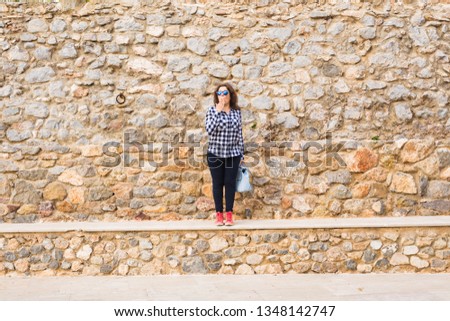 Young funny emotional woman with handbag posing on stone urban background
