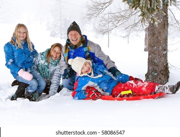 Young Funny Family With Sledge Under A Tree In Winter-landscape