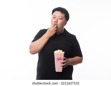 Young Funny Fat Asian Man Eating Popcorn Isolated On White Background, Unhealthy Concept.