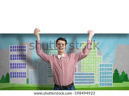Young funny guy in checked shirt holding blank banner above head