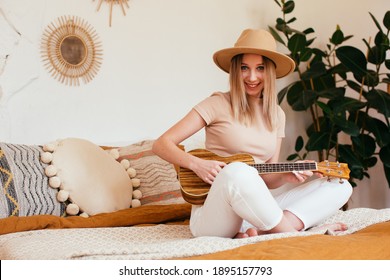 Young Funny Hipster Girl Having Fun And Playing On Small Ukulele Guitar, Singing And Dancing. Wearing A Hat, Joy, Positive Mood. Instagram Live Concert