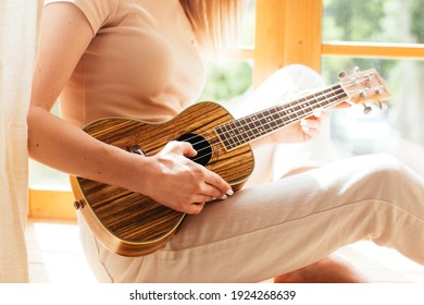 Young Funny Hipster Girl Having Fun And Playing On Small Ukulele Guitar In A Cabin, Positive Mood. Instagram Live Concert