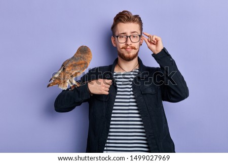 young funny man with owl in his arm. isolated blue background, cosplay, lifestyle, free time, spare time