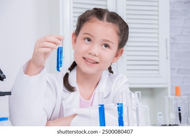 Young future scientist girl in white lab coat holding test tube with blue liquid, thoughtfully, curious, engaging in a science experiment in a laboratory with scientific equipment. education concept - Powered by Shutterstock