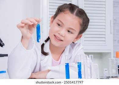 Young future scientist girl in white lab coat holding test tube with blue liquid, thoughtfully, curious, engaging in a science experiment in a laboratory with scientific equipment. education concept - Powered by Shutterstock