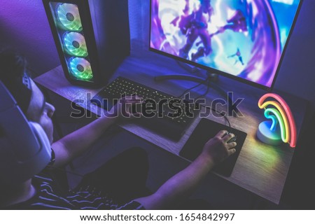 Young gamer playing at online game - Male guy having fun gaming and streaming online - New technology game trends and entertainment concept - Soft focus on right hand