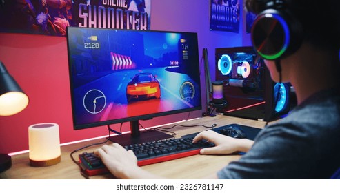 Young gamer plays in car racing simulator on PC at home. Computer monitor with displayed online video game live stream or cybersport championship. Desk illuminated by RGB LED strip light. - Powered by Shutterstock