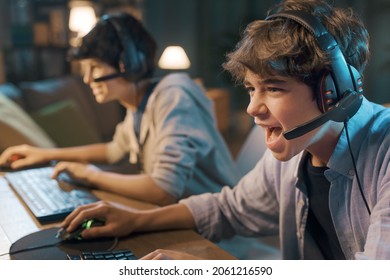 Young gamers sitting at desk and playing online video games together, one is shouting into the microphone - Powered by Shutterstock