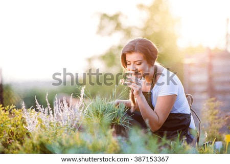 Young gardener in garden smelling flower, sunny nature