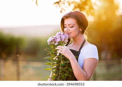 Young Gardener In Her Garden Smelling Flowers, Sunny Nature