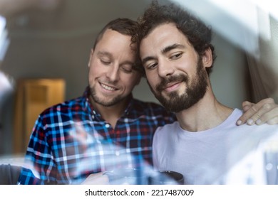 Young Gay Couple In Love Looking Out The Window. Two Young Androgynous Men Smiling Together And Having Coffee.