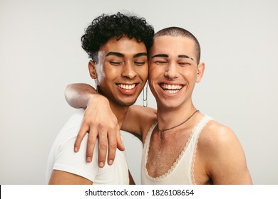 Young gay couple in love on a white background. Two young androgynous men smiling together.