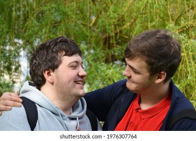 Young Gay Couple Lovingly Chatting And Laughing With Each Other While Holding Hands In A Spring Park