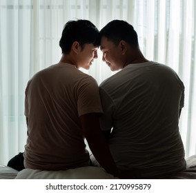 Young Gay Couple Sitting Next Together In The Room, Enjoying Togetherness, Looking Into The Future. Love And Bonding Concept.