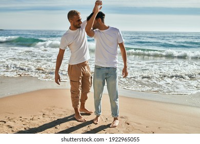 Young gay couple smiling happy dancing at the beach.