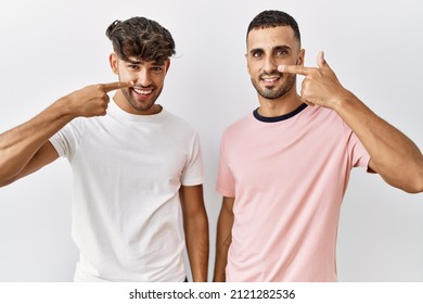 Young Gay Couple Standing Over Isolated Background Pointing With Hand Finger To Face And Nose, Smiling Cheerful. Beauty Concept 