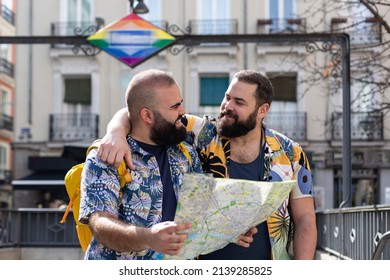 Young Gay Couple With Tourist Map At The Exit Of A Transport Station. Concept Of People Traveling And Vacation.