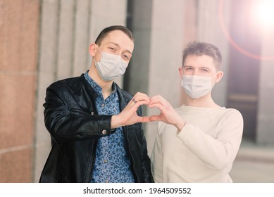 Young Gay Couple Wearing Medical Mask, Hugging And Kissing At City.