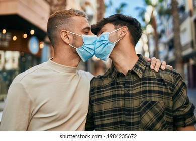 Young Gay Couple Wearing Medical Mask Kissing At The City.