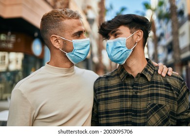 Young Gay Couple Wearing Medical Mask Hugging At The City.