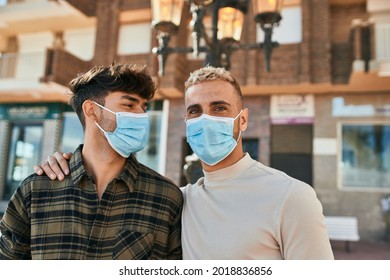 Young Gay Couple Wearing Medical Mask Hugging At The City.