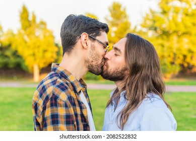 A Young Gay Male Couple Kissing In The Park.