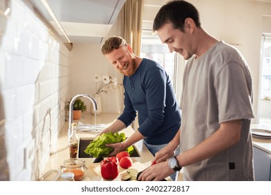 Young gay male couple preparing healthy vegetarian meal in the kitchen - Powered by Shutterstock