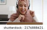 Young Gen Z workforce islam woman video call fun talk on webcam laptop work at home office. Asia people arab hijab scarf girl smile study relax remote learn online share job idea on digital webinar.