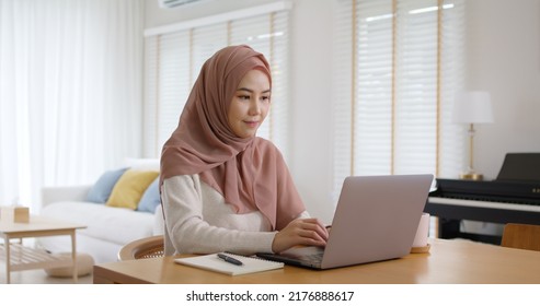 Young Gen Z Workforce Islam Woman Self Learn MBA Online Class Reskill Upskill Job At Home. Asia People Arab Girl Study Relax Sit At Table Wear Hijab Scarf Write Or Typing E-mail Work On Digital Laptop