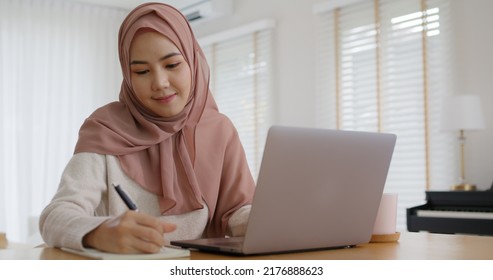 Young Gen Z Workforce Islam Woman Self Learn MBA Online Class Reskill Upskill Job At Home. Asia People Arab Girl Study Relax Sit At Table Wear Hijab Scarf Write Or Typing E-mail Work On Digital Laptop