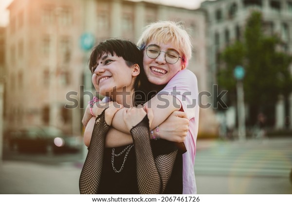 Young gender\
fluid couple hugging on city\
street\
