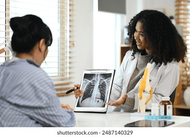 Young general practitioner explaining results of lung check up from x-ray scan chest to patient