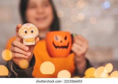 Young Generations Z Teen Boy In Orange Clothes While All Hallows Eve Photo Session At Home. Stylish Teenager With Cup Of Head Jack And Sweets Celebrates Halloween Holiday Enjoy Chocolate Candy