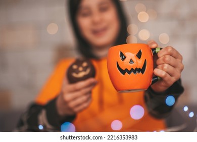 Young Generations Z Teen Boy In Orange Clothes While All Hallows Eve Photo Session At Home. Stylish Teenager With Cup Of Head Jack And Sweets Celebrates Halloween Holiday Enjoy Chocolate Candy