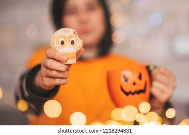 Young Generations Z Teen Boy In Orange Clothes While All Hallows Eve Photo Session At Home. Stylish Teenager With Cup Of Head Jack And Sweets Celebrates Halloween Holiday Enjoy Chocolate Candy