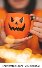 Young generations Z teen boy in orange clothes while all hallows eve photo session at home. Stylish teenager with cup of head Jack and sweets celebrates halloween holiday enjoy chocolate candy - Shutterstock ID 2232808003