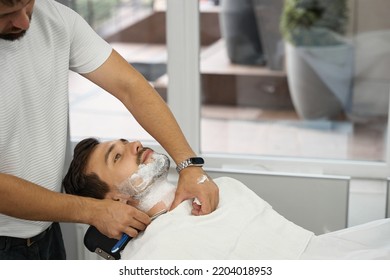 Young Gentleman Having Beard Shaved And Groomed At Local Barbershop