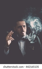 Young Gentleman Are Smoking Cigar With Black Background.