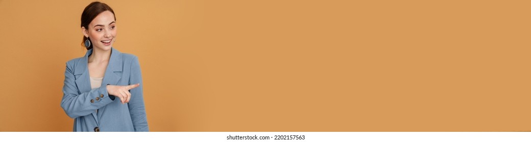 Young Ginger Woman Smiling And Pointing Finger Aside Isolated Over Yellow Background