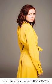 Young ginger woman in yellow shirt dress. Female bright look, lemon casual style. Fashion portrait on neutral studio background.