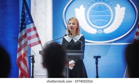 Young Girl Activist Delivering An Emotional And Powerful Speech At Press Conference In Government Building. Child Speaking To Congress At Summit Meeting. Backdrop With United States Of America Flags.