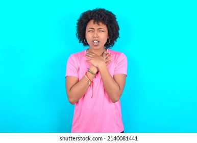 young girl with afro hair style wearing sport pink t-shirt over blue background shouting suffocate because painful strangle. Health problem. Asphyxiate and suicide concept.