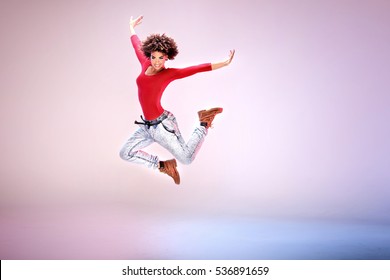 Young girl with afro jumping, flying, dancing in studio.