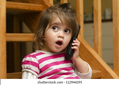 Young girl (age 3) speaking on the phone at home. Concept photo of long distance ,call ,communication, telephone, service, overseas, conversation, technology. Real people. Copy space