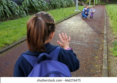 Young Girl (age 6-7) Going To School Wave Goodbye To Her Mother. People Education Concept