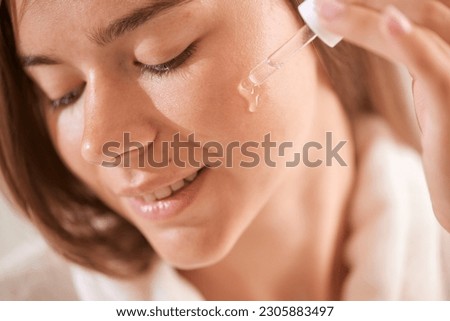 young girl applying vitamins to her face at home, skin care concept