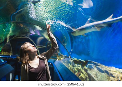 Young girl in aquarium tunnel with sharks
