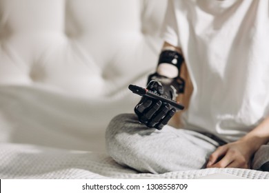 young girl with an artificial arm pressing the buttons on the remote control, development of medicine. close up cropped photo. touching skills